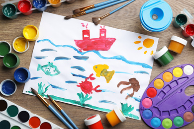 Flat lay composition with child's painting of underwater life on wooden table