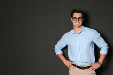 Photo of Handsome young man in stylish clothes with glasses on dark background. Space for text