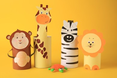 Photo of Toy monkey, giraffe, lion and zebra made from toilet paper hubs on yellow background. Children's handmade ideas