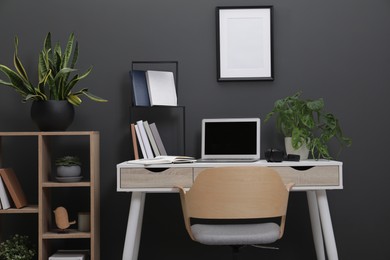 Workplace with laptop, stationery on desk and chair in home office