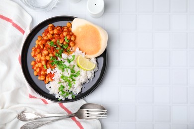 Photo of Delicious chickpea curry with rice served on white tiled table, flat lay. Space for text