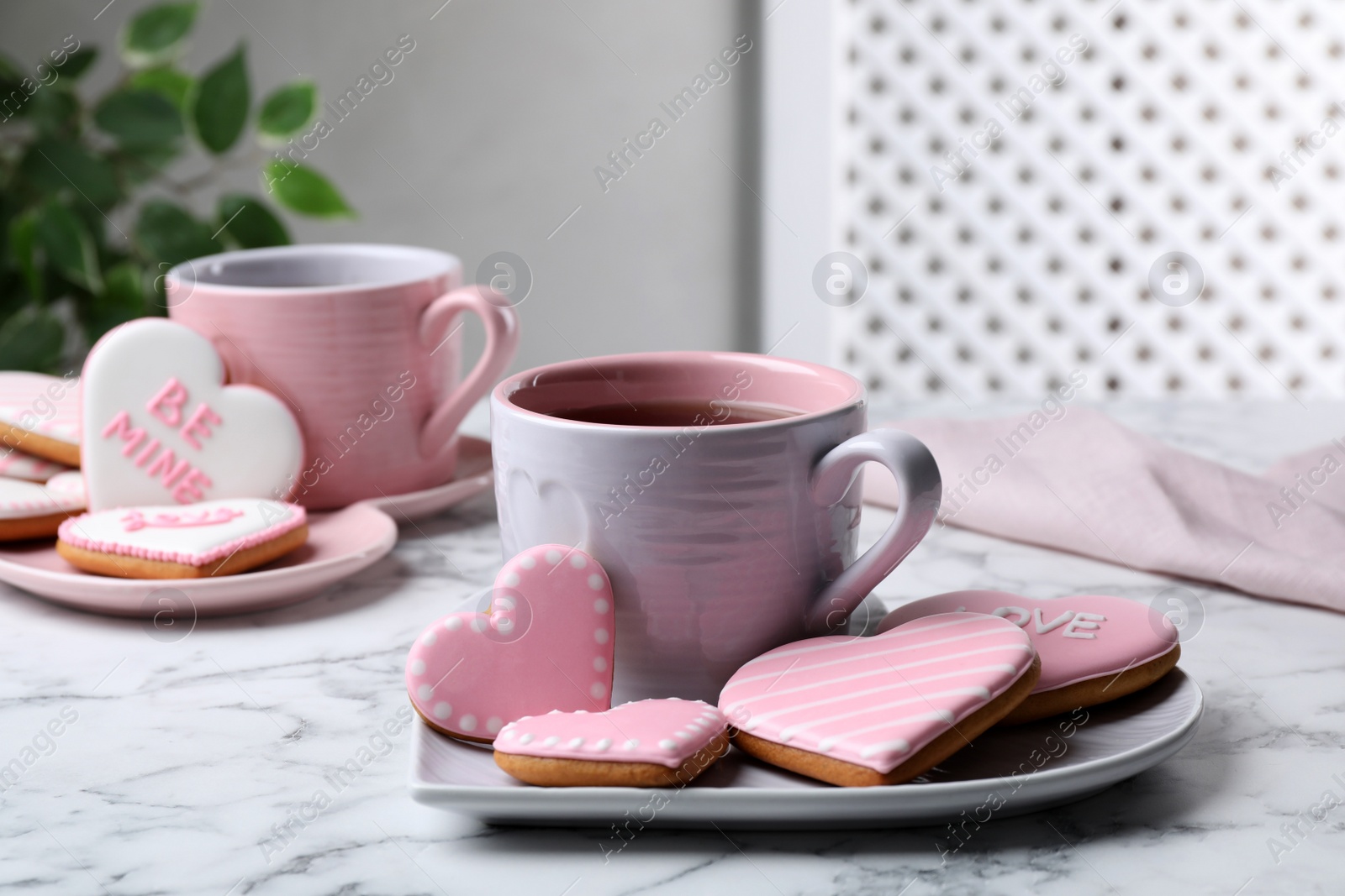 Photo of Delicious heart shaped cookies and cup of tea on white marble table