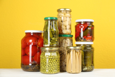 Photo of Jars of pickled vegetables on white wooden table