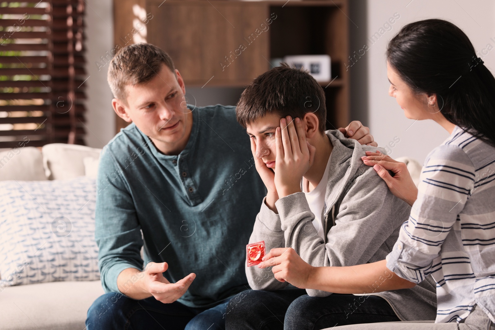 Photo of Parents talking with their teenage son about contraception at home. Sex education concept