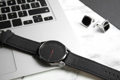 Photo of Stylish wrist watch and laptop on marble table. Time management