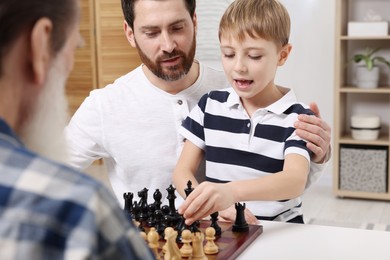 Family playing chess together at table in room