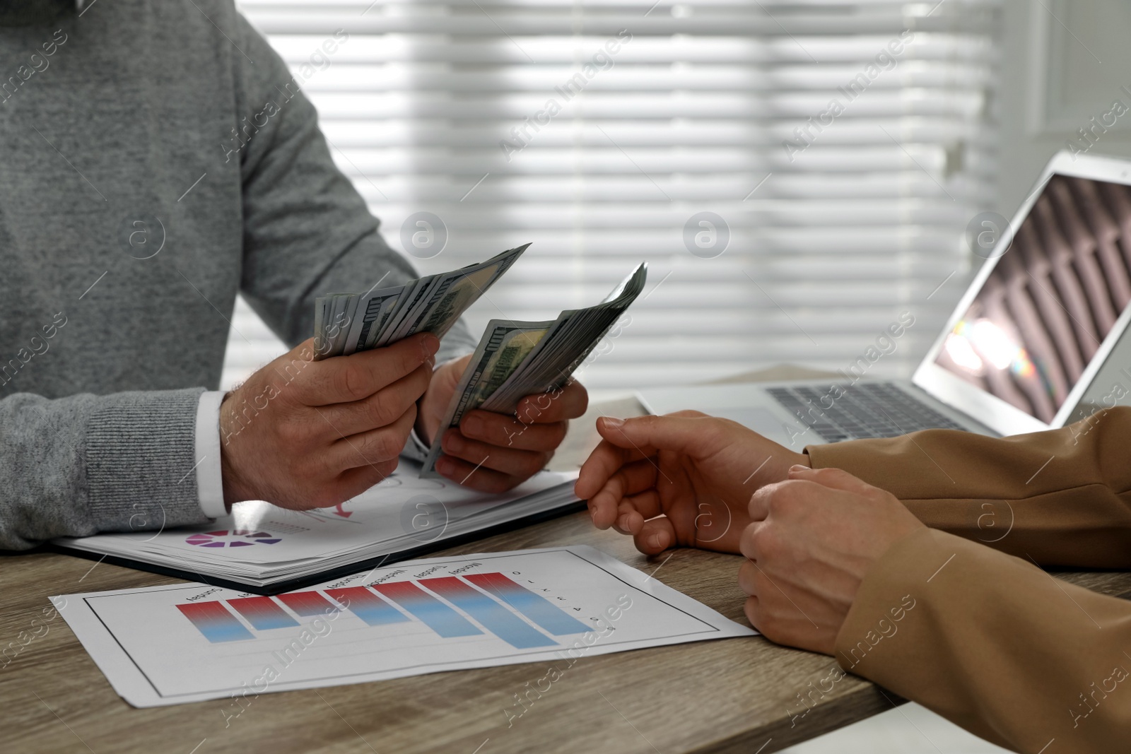 Photo of Cashier giving money to businesswoman at desk in bank, closeup