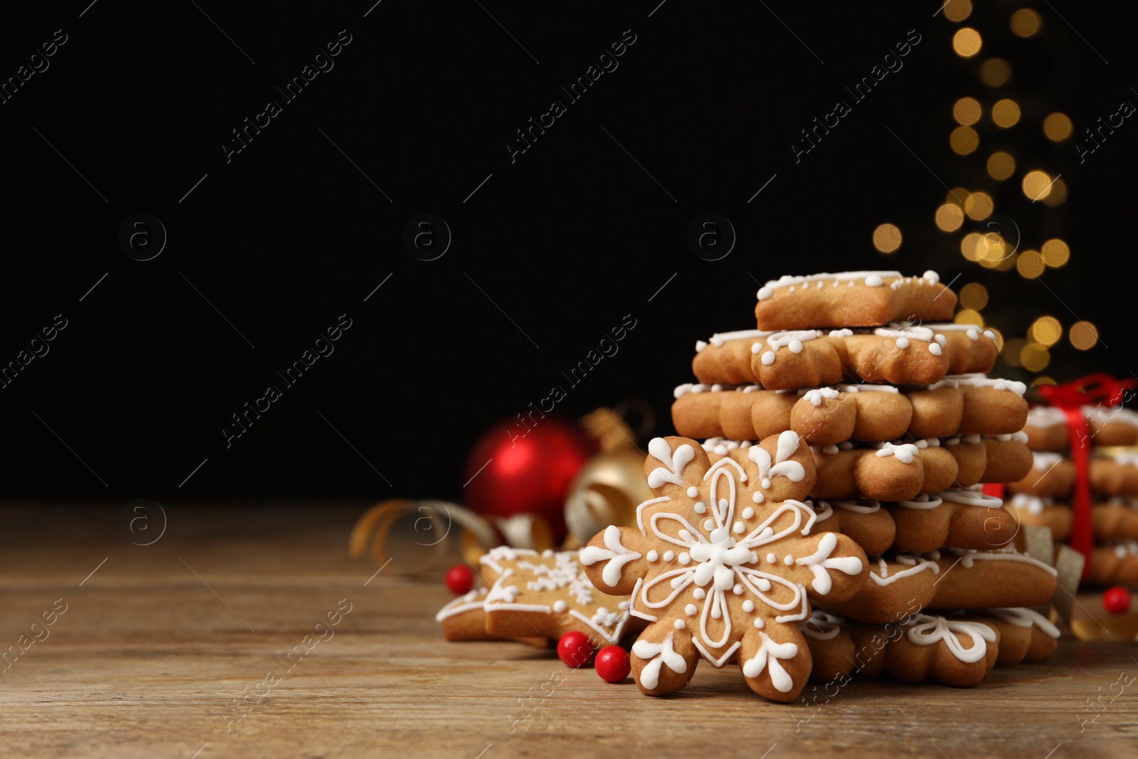 Photo of Tasty Christmas cookies on wooden table against blurred festive lights, space for text