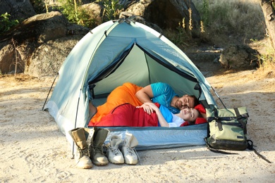 Young couple resting in sleeping bags inside tent