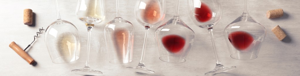 Glasses with different wines on light grey background, flat lay. Banner design