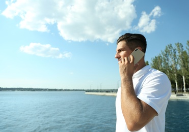 Man talking on modern mobile phone near river