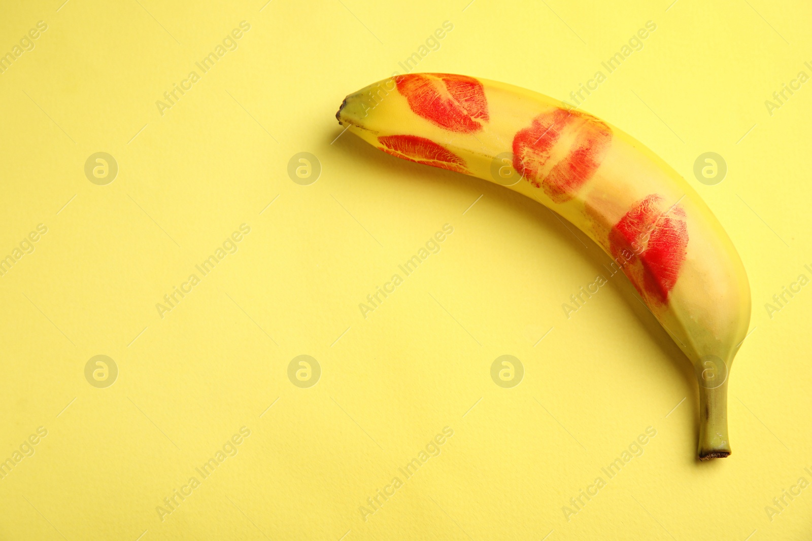 Photo of Fresh banana with red lipstick marks on yellow background, space for text. Oral sex concept