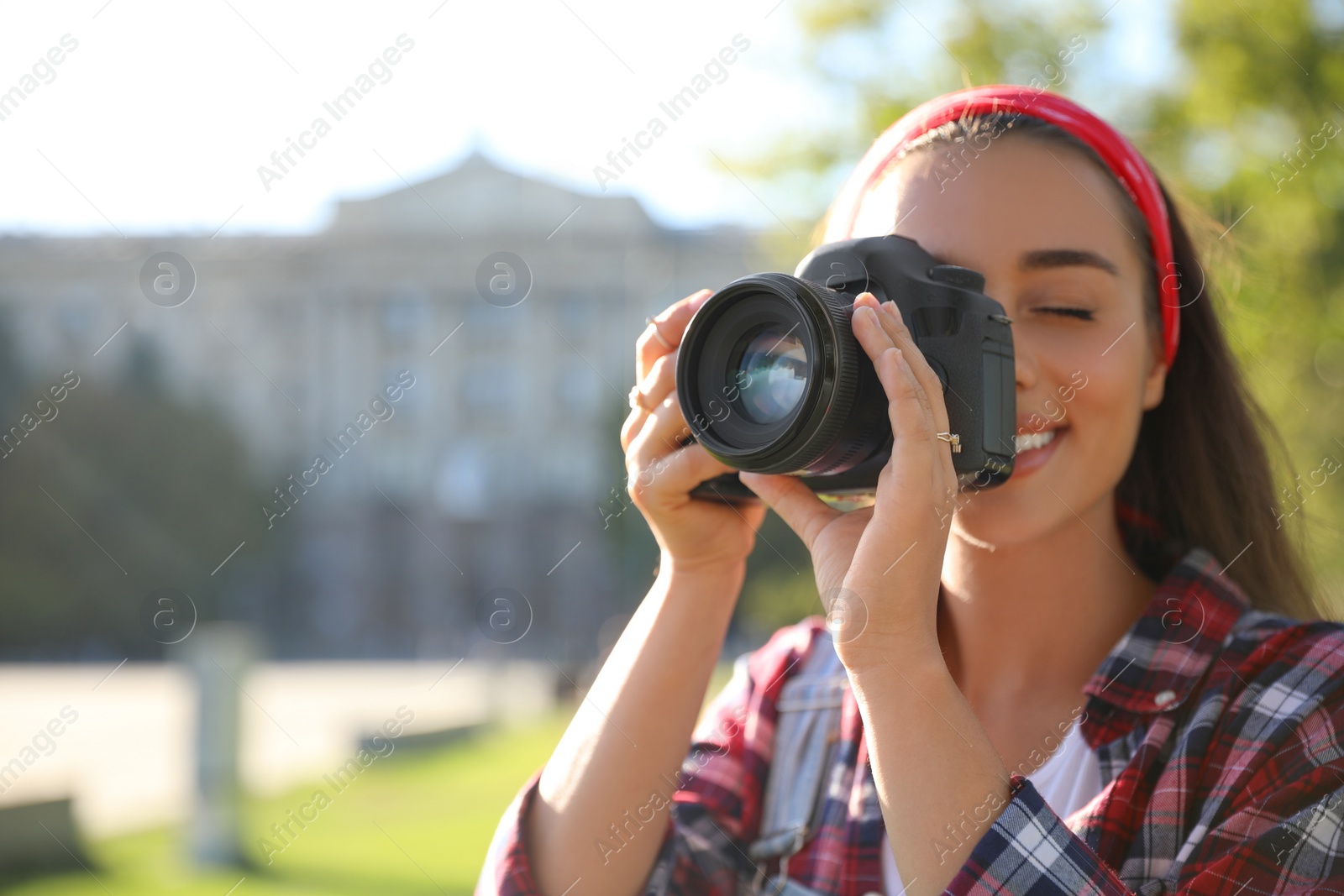 Photo of Young photographer taking picture with professional camera outdoors. Space for text