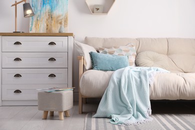 Photo of Stylish living room interior with ottoman, sofa and white wooden chest of drawers