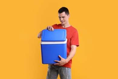 Man with blue cool box on orange background