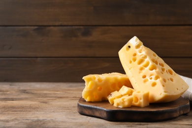 Photo of Pieces of delicious cheese on wooden table, space for text