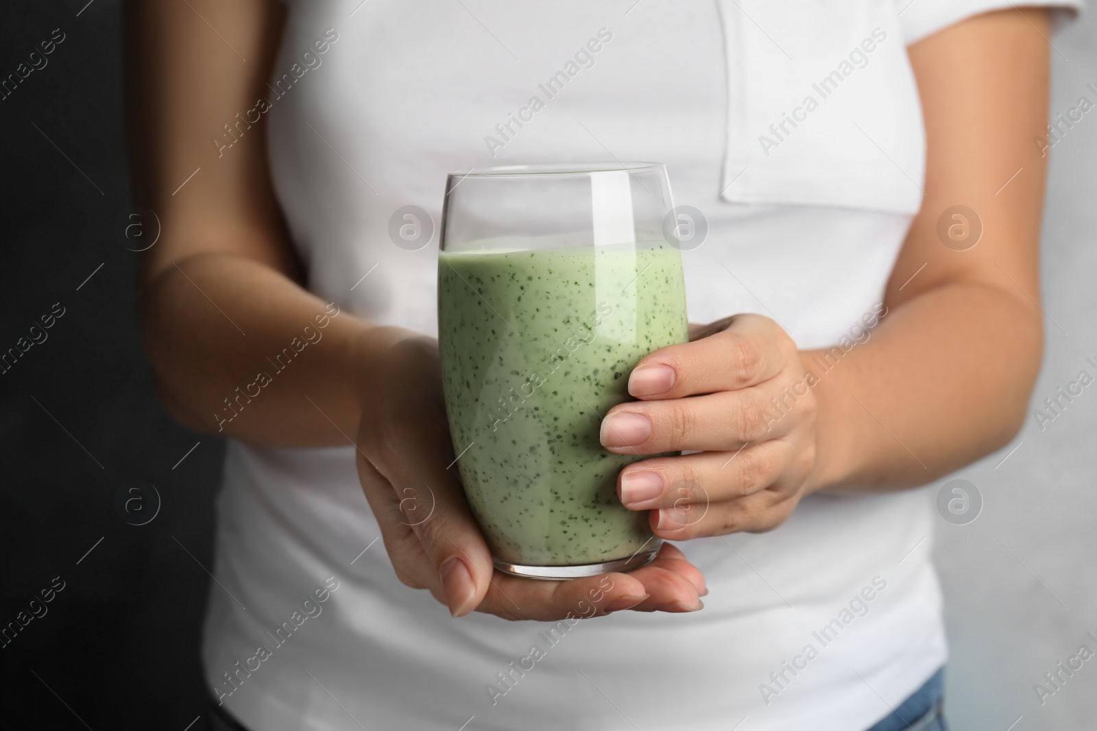 Photo of Woman holding green buckwheat smoothie, closeup view