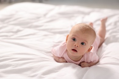 Photo of Cute little baby lying on white sheets, space for text