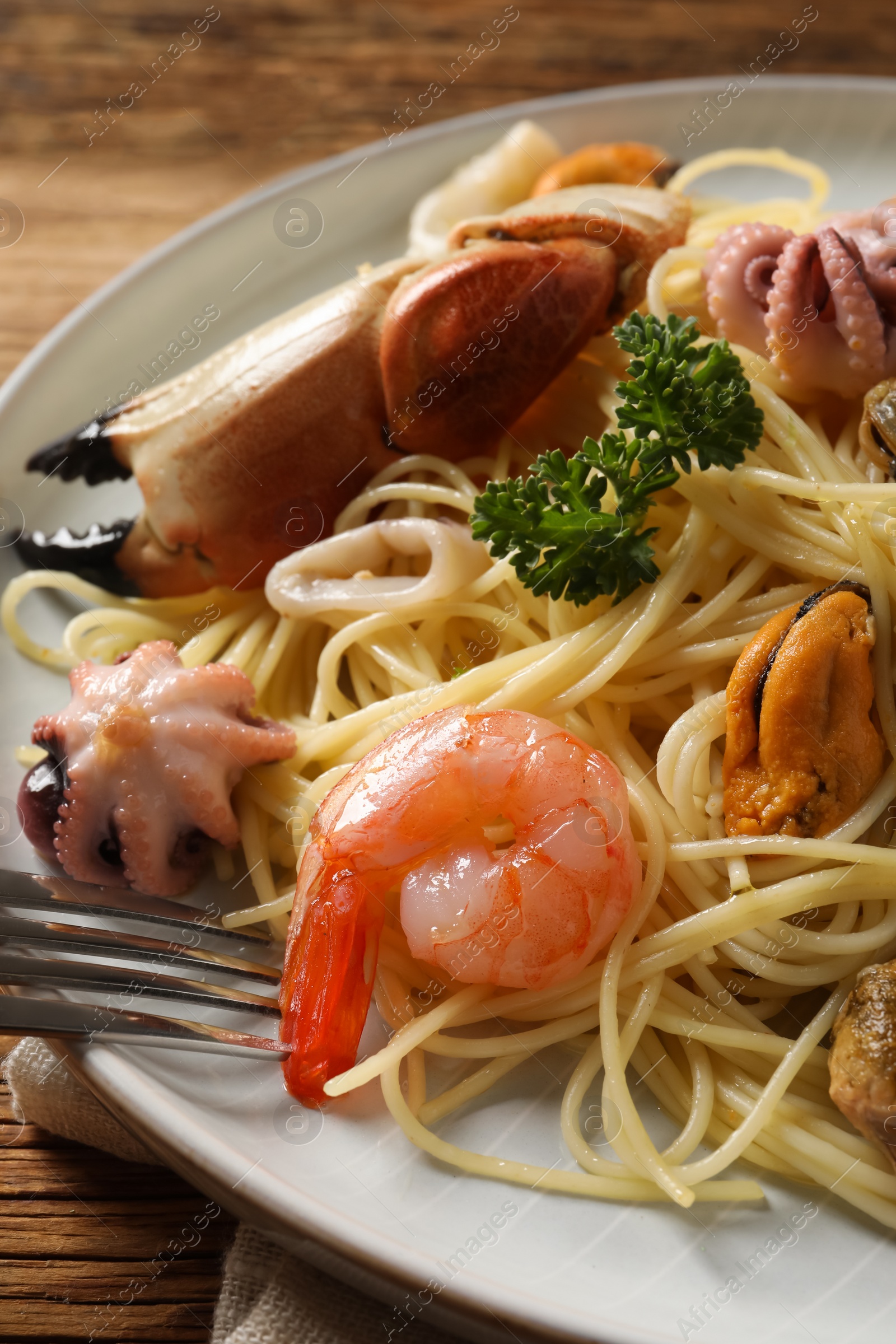 Photo of Delicious spaghetti with seafood served on wooden table, closeup