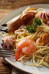 Delicious spaghetti with seafood served on wooden table, closeup