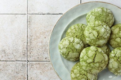 Photo of Plate with tasty matcha cookies on tiled table, top view. Space for text