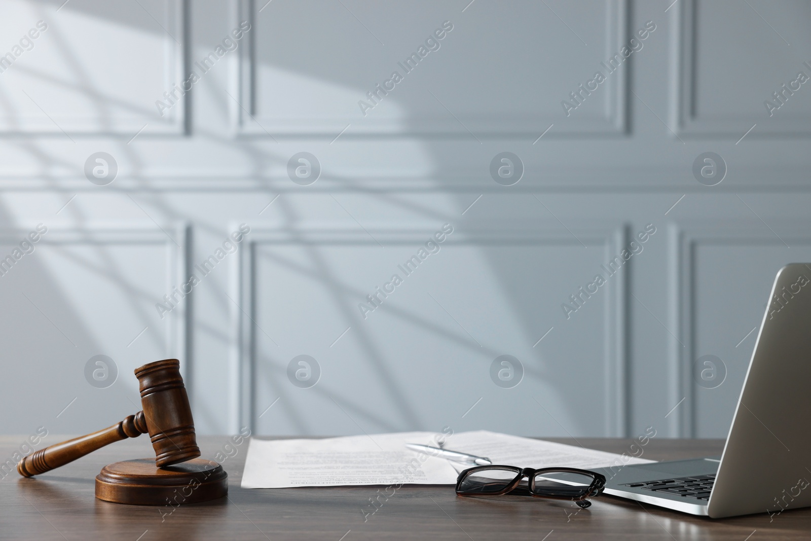 Photo of Gavel, papers, glasses and laptop on wooden table indoors. Judge workplace