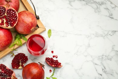 Photo of Tasty pomegranate juice in glass and fresh fruits on white marble table, flat lay. Space for text