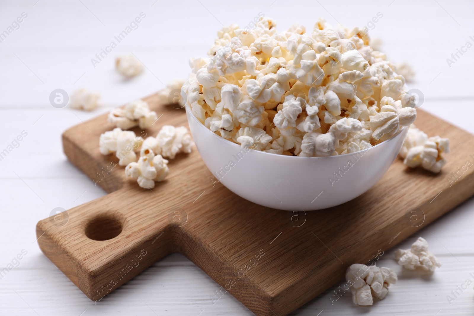 Photo of Tasty popcorn in bowl on white wooden table