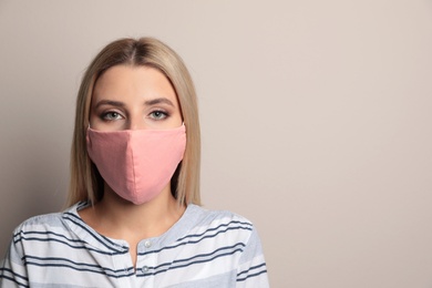 Photo of Young woman in protective face mask on beige background. Space for text