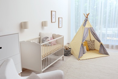 Photo of Cozy baby room interior with play tent and toys