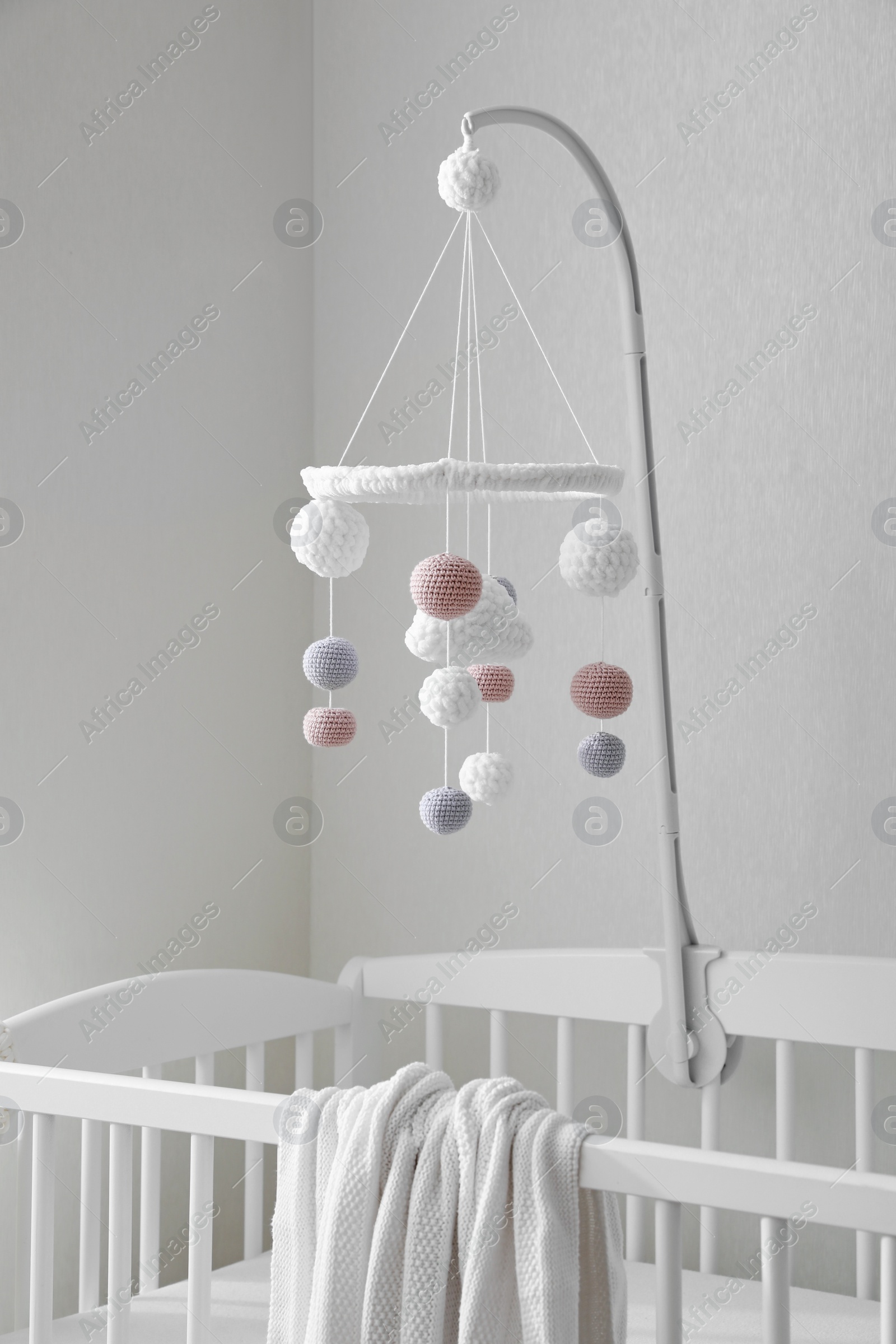 Photo of Modern crib with baby mobile in children's room. Interior design
