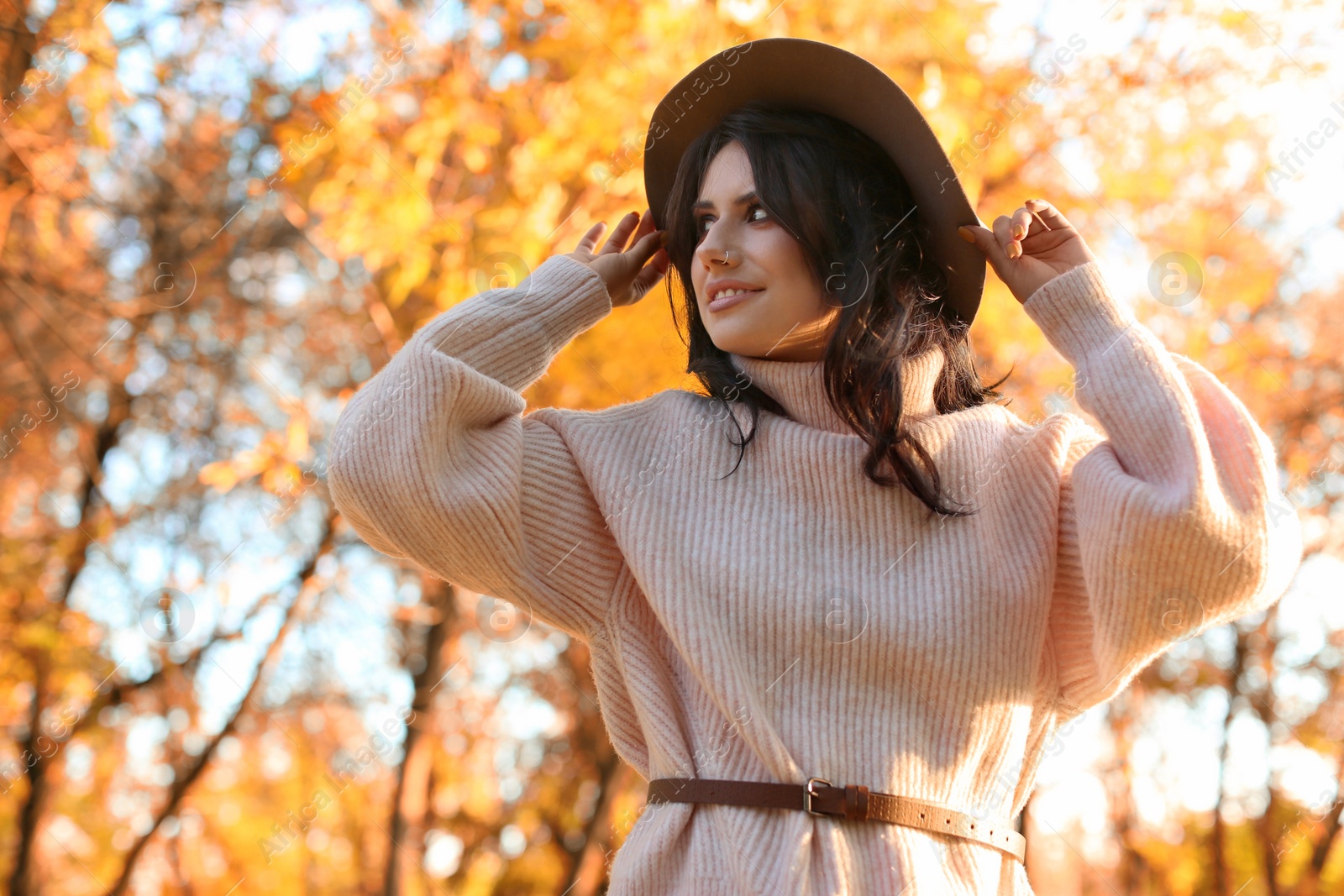 Photo of Beautiful young woman wearing stylish sweater in autumn park