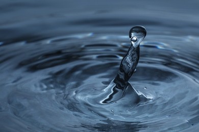 Photo of Splash of clear water with drops on dark blue background, closeup