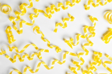 Photo of Yellow serpentine streamers on white background, top view