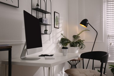 Comfortable workplace with modern computer and houseplants in room. Interior design