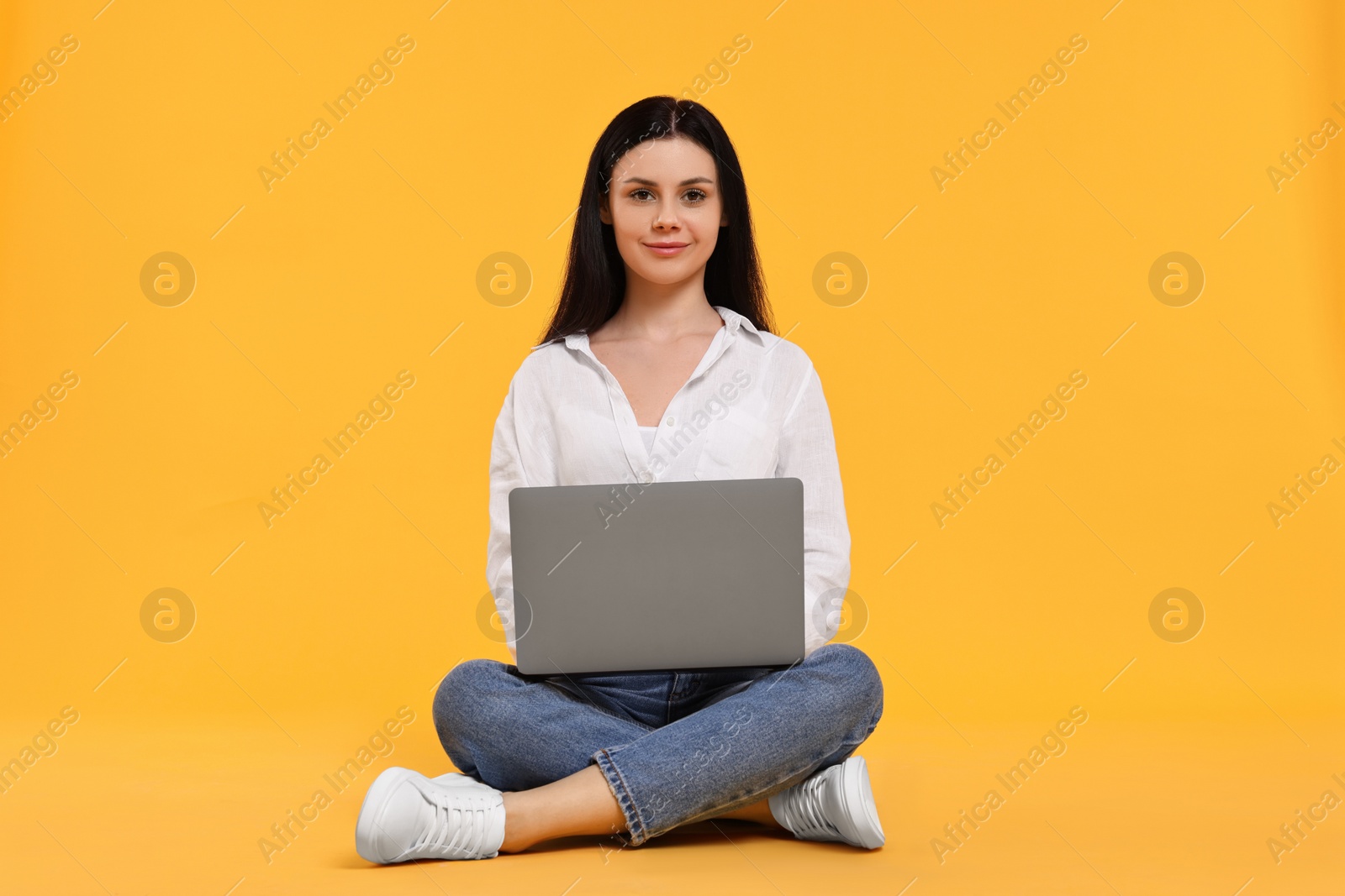 Photo of Student with laptop sitting on yellow background