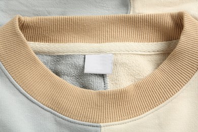 Photo of Blank clothing label on stylish sweater, top view