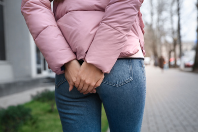 Woman suffering from hemorrhoid pain outdoors, closeup
