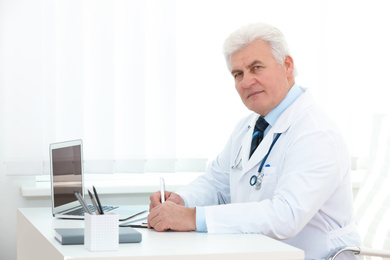 Portrait of senior doctor in white coat at workplace