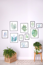 Photo of Beautiful paintings of tropical leaves on white wall in living room interior