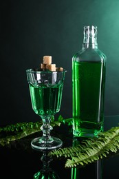 Absinthe, brown sugar and green leaves on mirror table. Alcoholic drink