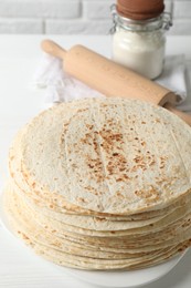 Tasty homemade tortillas, flour and rolling pin on table