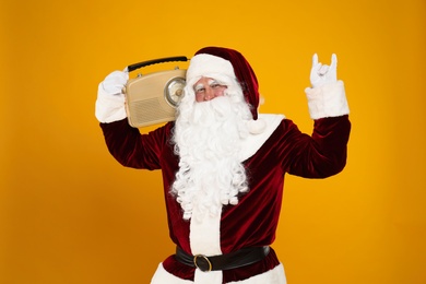 Photo of Santa Claus with vintage radio on yellow background. Christmas music