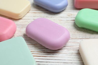 Photo of Many different soap bars on wooden table, closeup