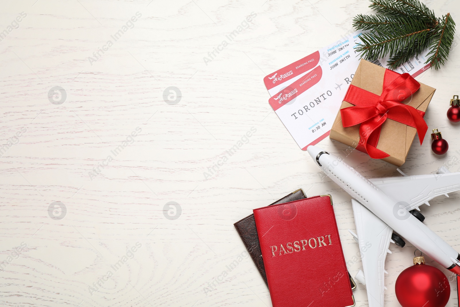 Photo of Flat lay composition with Christmas decorations, passports and airline tickets on white wooden table, space for text. Winter vacation