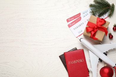 Photo of Flat lay composition with Christmas decorations, passports and airline tickets on white wooden table, space for text. Winter vacation