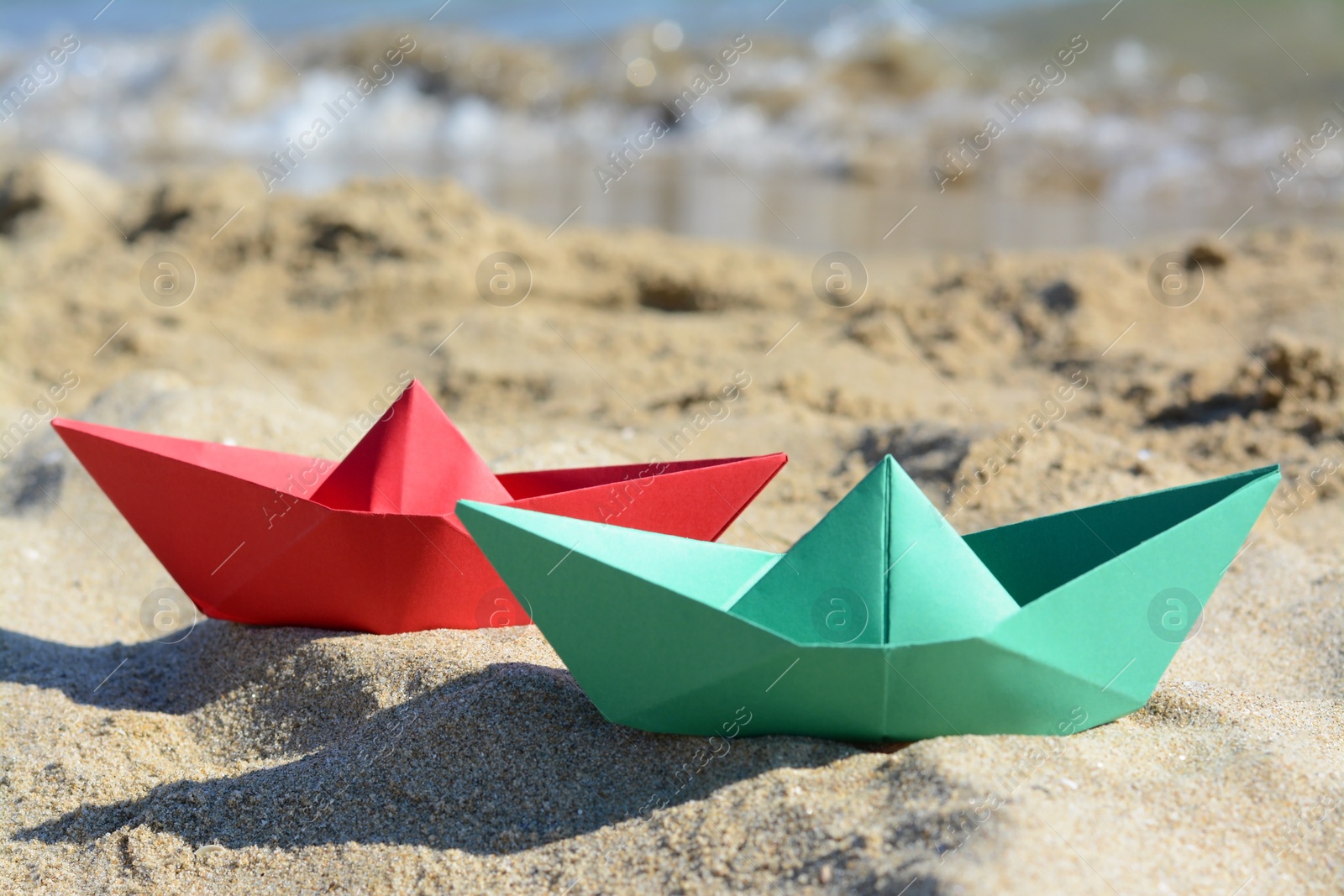 Photo of Two paper boats near sea on sunny day, closeup