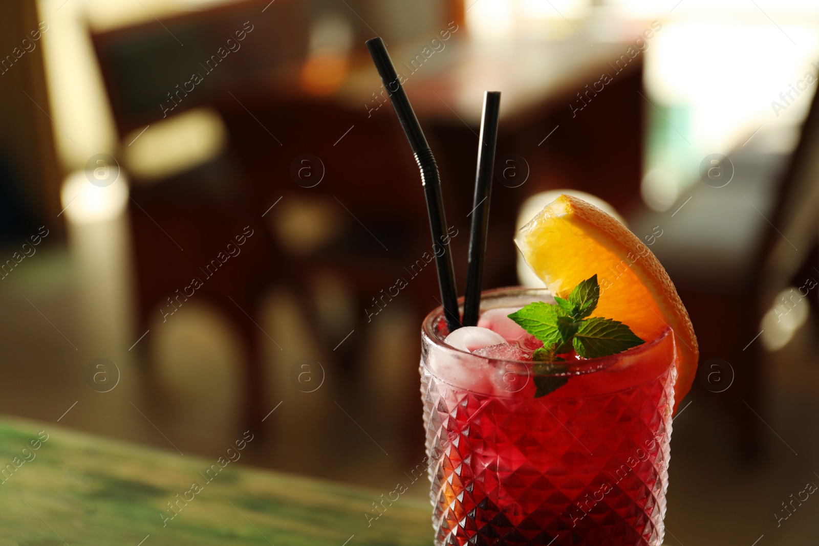 Photo of Glass of delicious cocktail with ice on blurred background, closeup