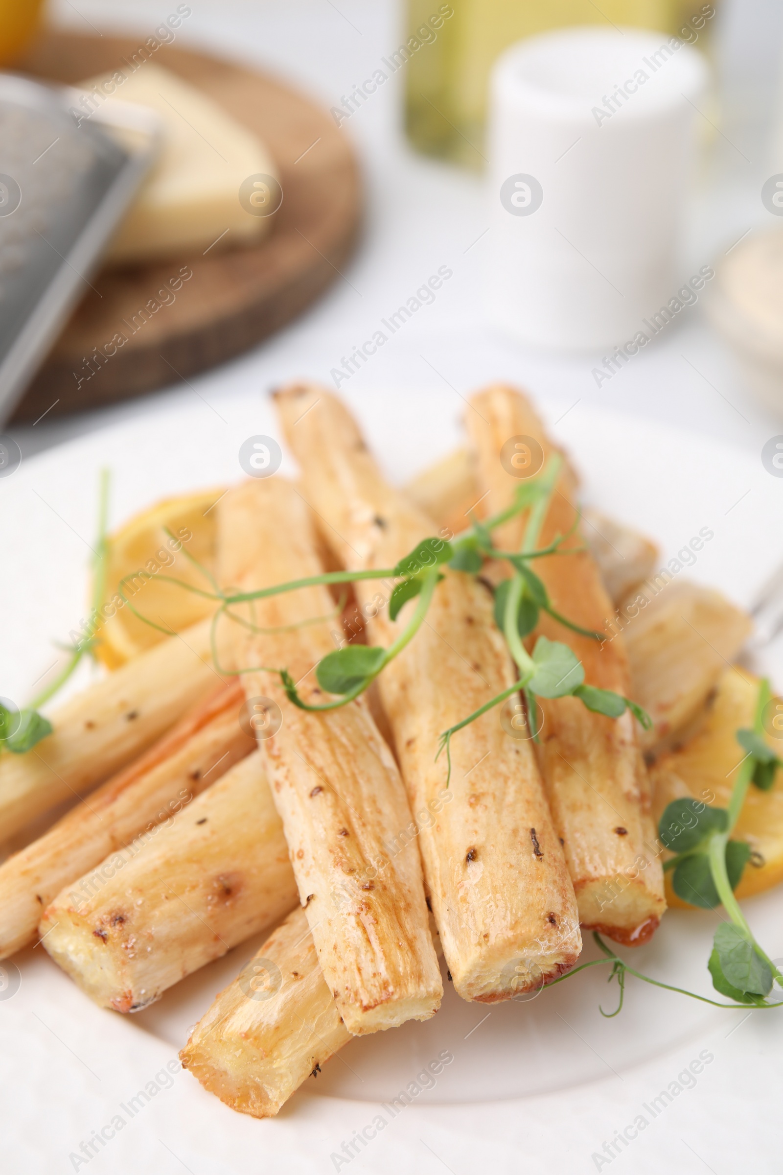 Photo of Plate with baked salsify roots and lemon on table, closeup