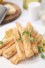 Plate with baked salsify roots and lemon on table, closeup